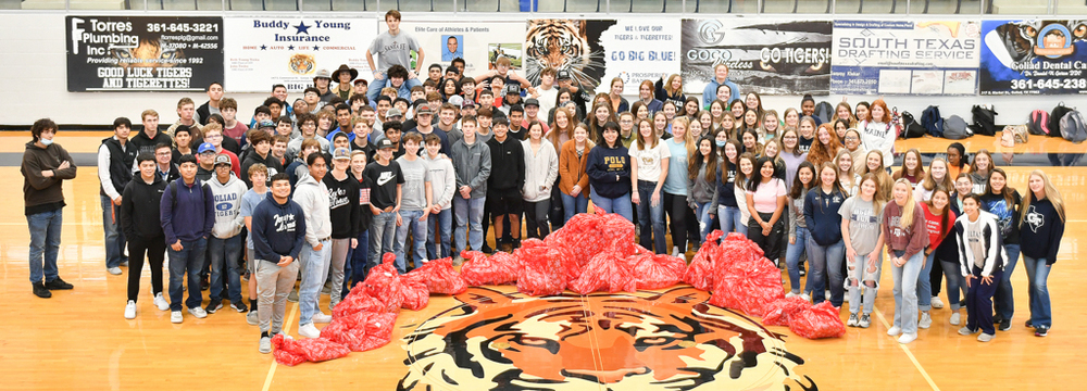 Students pose for a photo with the bags of presents collected for 16 children in Goliad County this Christmas.